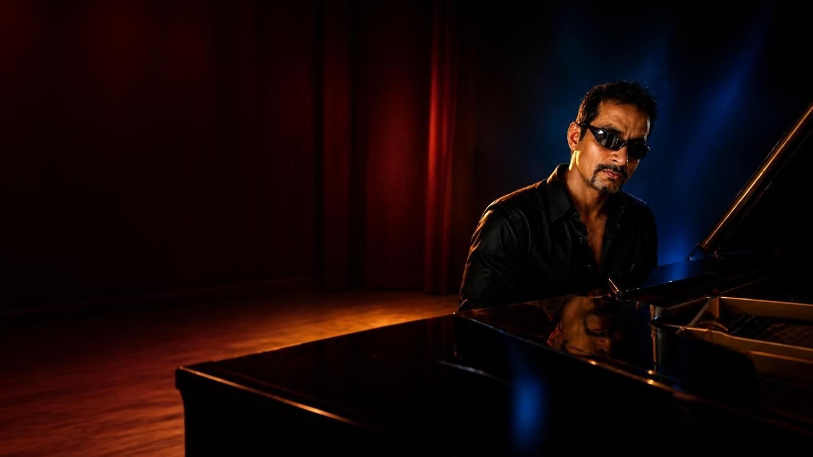 Imran Behleem at a grand piano on a dim stage